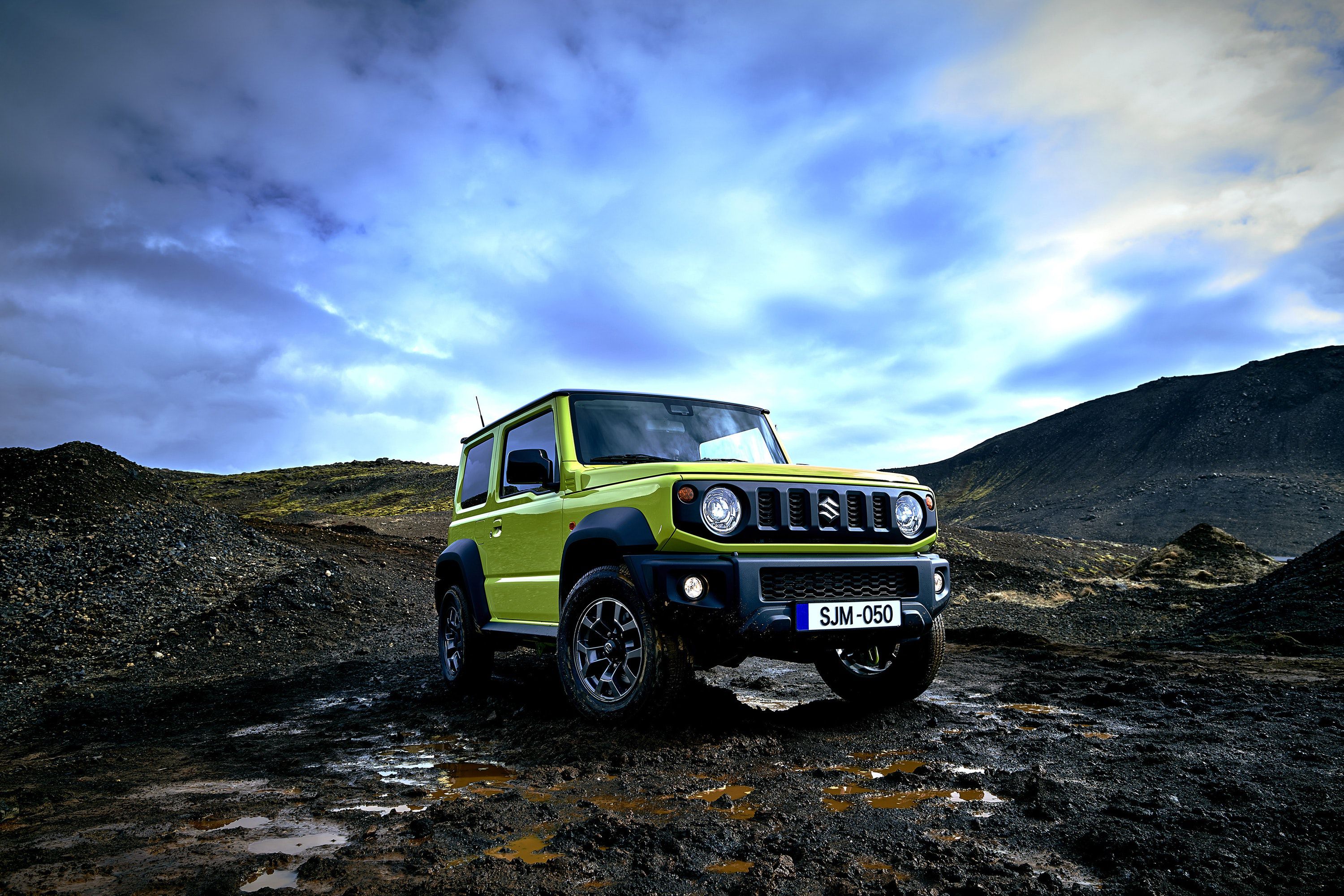 Lime green Suzuki Jimny parked on top of a rocky mountain